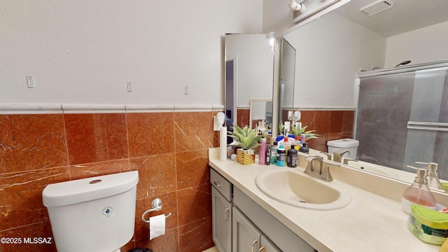 bathroom featuring tile walls, toilet, vanity, and an enclosed shower