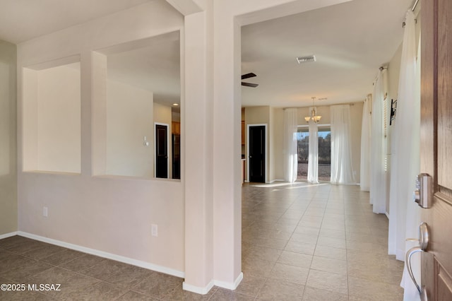 corridor with a notable chandelier and tile patterned floors