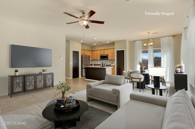 unfurnished living room with light tile patterned flooring, ceiling fan with notable chandelier, and sink