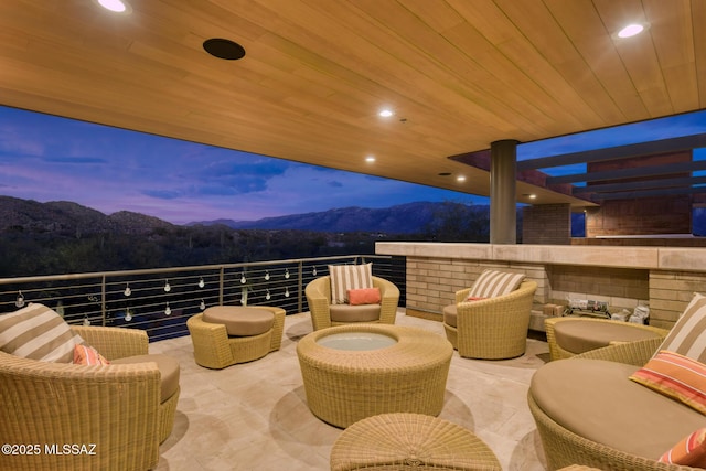 patio terrace at dusk with a balcony, an outdoor hangout area, and a mountain view