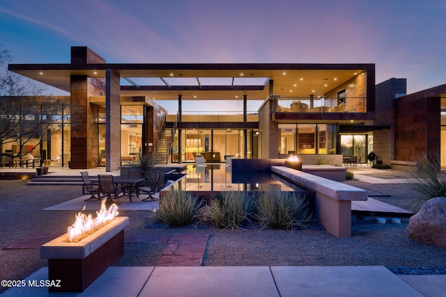 patio terrace at dusk featuring a balcony and a fire pit