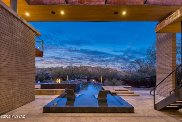 pool at dusk with a fire pit, a patio, and a jacuzzi