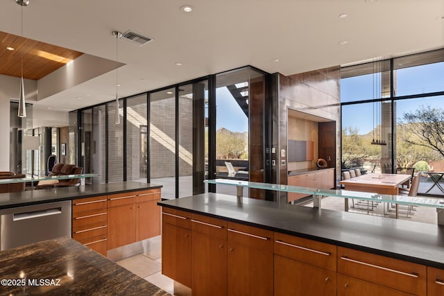 kitchen featuring light tile patterned flooring, stainless steel dishwasher, and a wall of windows