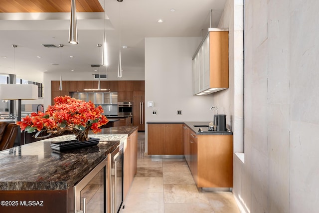 kitchen featuring beverage cooler, decorative light fixtures, sink, and a kitchen island