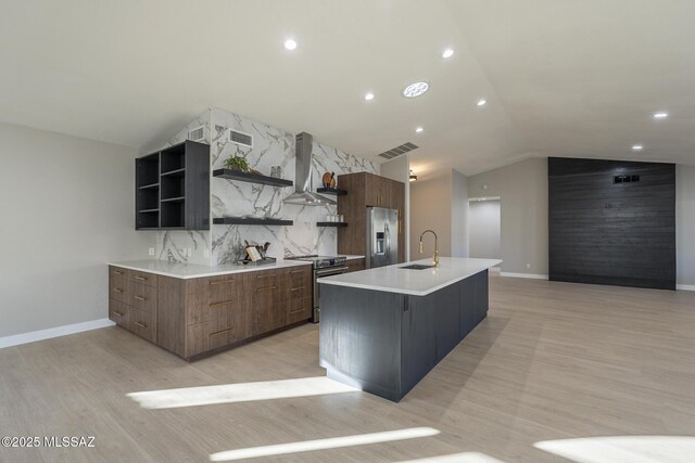 kitchen with a center island with sink, stainless steel appliances, light wood-type flooring, a chandelier, and sink