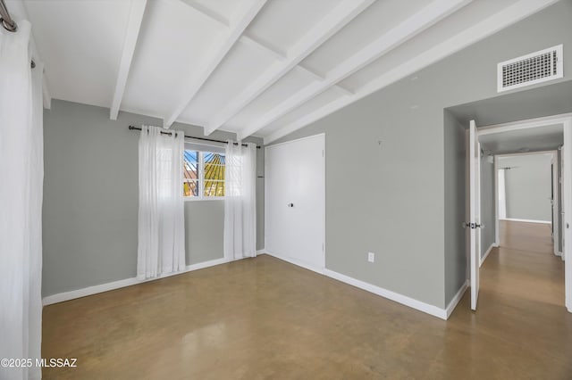 unfurnished room with lofted ceiling with beams and concrete flooring