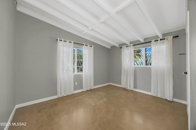 unfurnished room with concrete floors, a wealth of natural light, and vaulted ceiling with beams