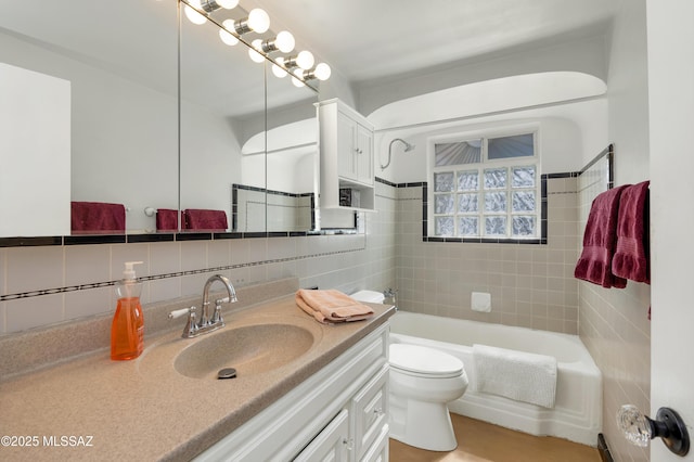 bathroom with tile walls, toilet, vanity, and tasteful backsplash