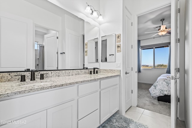 ensuite bathroom with ceiling fan, double vanity, a sink, and tile patterned floors