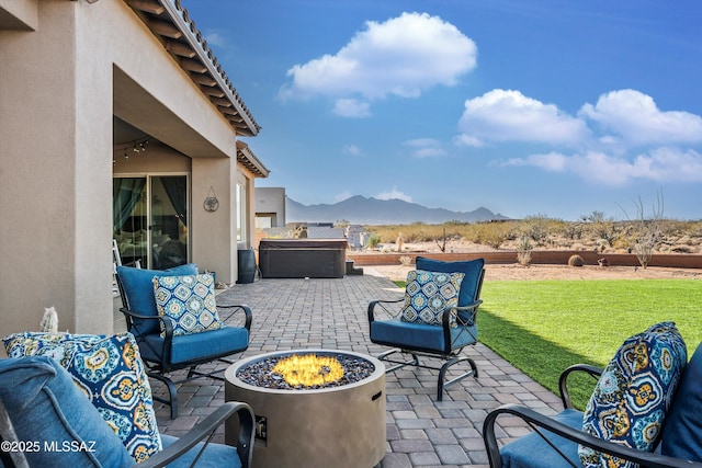 view of patio with an outdoor fire pit, a mountain view, and a hot tub