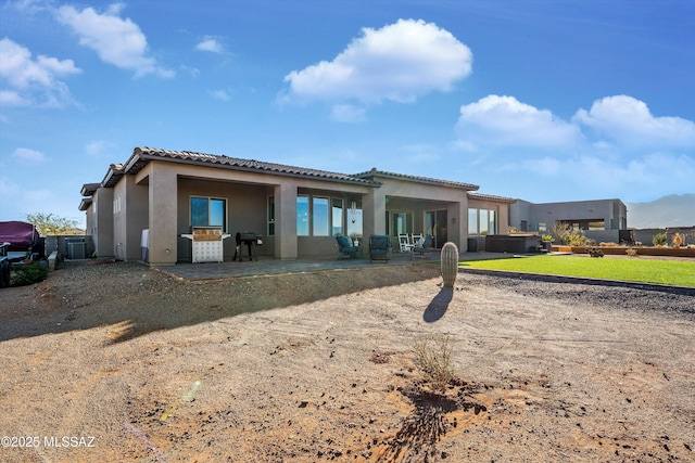 rear view of property featuring a patio area, a tile roof, and stucco siding