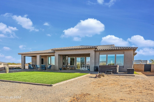 rear view of house featuring a yard, a hot tub, and a patio area