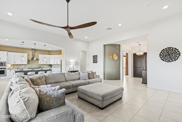 living area featuring arched walkways, light tile patterned floors, recessed lighting, visible vents, and ceiling fan