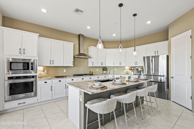 kitchen with light tile patterned flooring, stainless steel appliances, a sink, visible vents, and wall chimney exhaust hood