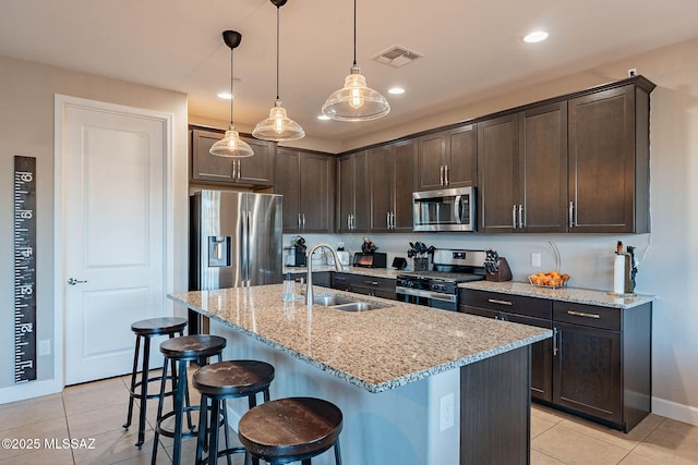 kitchen with stainless steel appliances, sink, pendant lighting, and dark brown cabinetry