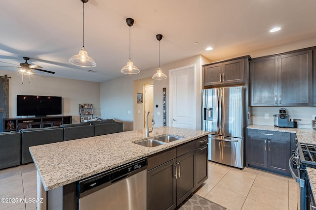 kitchen featuring sink, dark brown cabinets, light tile patterned floors, appliances with stainless steel finishes, and an island with sink