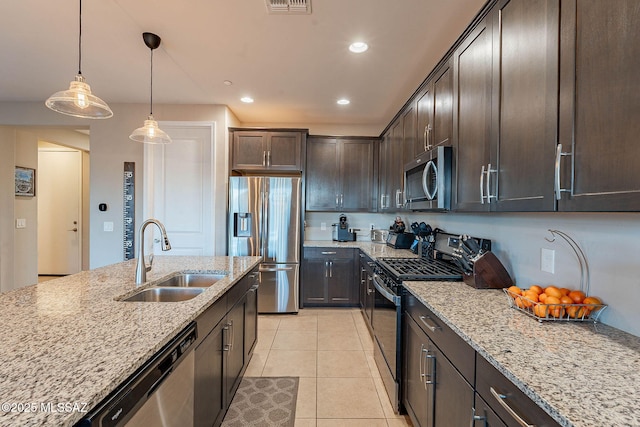 kitchen with light tile patterned flooring, sink, light stone counters, stainless steel appliances, and dark brown cabinets