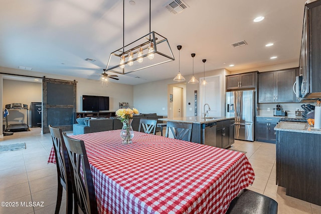 tiled dining space with sink, a barn door, and ceiling fan