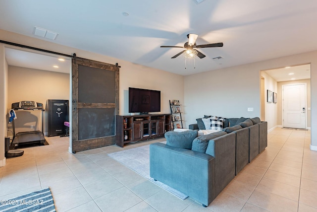 tiled living room with a barn door and ceiling fan