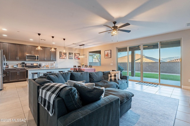 living room with a mountain view, light tile patterned floors, and ceiling fan