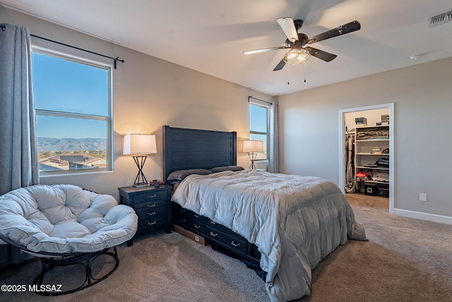 carpeted bedroom with a mountain view, a spacious closet, a closet, and ceiling fan