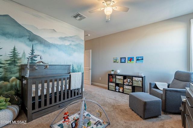 bedroom featuring a nursery area, ceiling fan, and light colored carpet