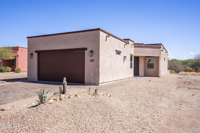pueblo-style house with stucco siding, decorative driveway, and a garage