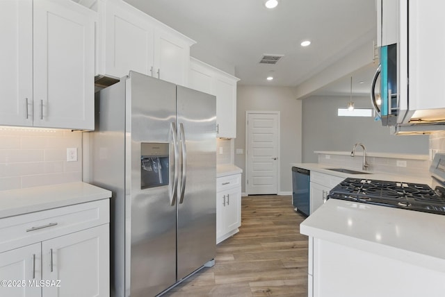 kitchen with a sink, stainless steel appliances, visible vents, and light countertops