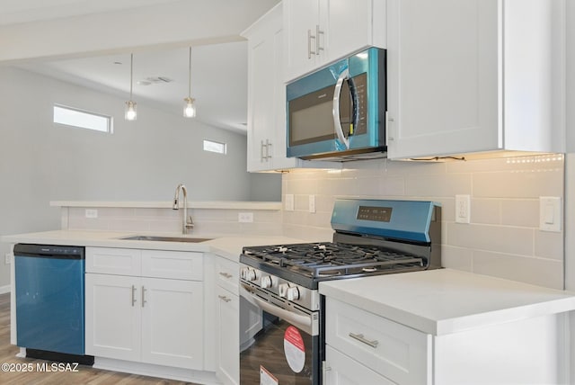 kitchen with a peninsula, a sink, decorative backsplash, light countertops, and appliances with stainless steel finishes