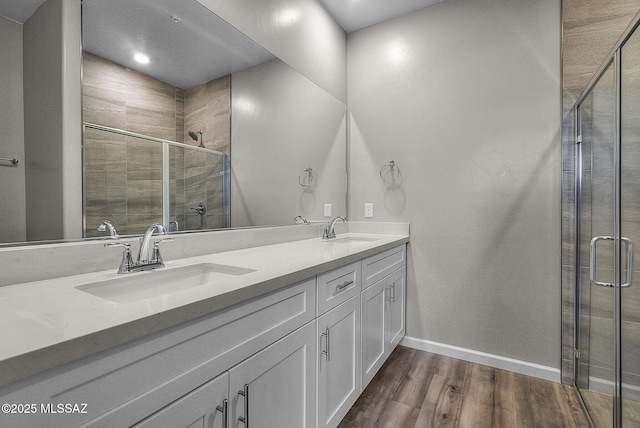 bathroom featuring a sink, double vanity, wood finished floors, and a shower stall