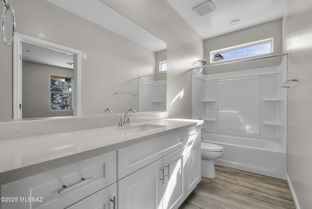 full bathroom with visible vents, toilet, vanity, wood finished floors, and washtub / shower combination
