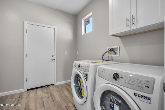 laundry room featuring light wood finished floors, baseboards, cabinet space, and washer and clothes dryer