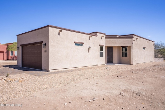 pueblo-style house with a garage and stucco siding