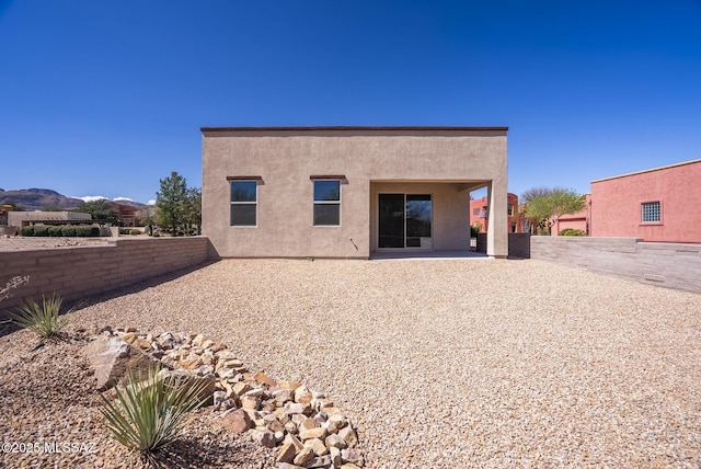 rear view of property featuring stucco siding, a patio, and fence