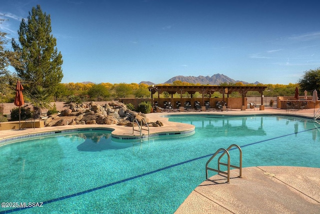 pool with a mountain view, fence, a pergola, and a patio area