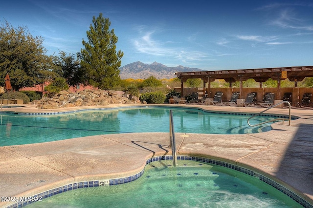 pool with a mountain view, a patio, and a community hot tub