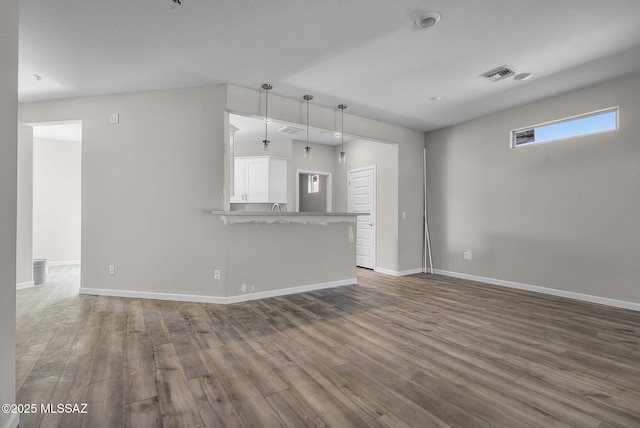 unfurnished living room with visible vents, baseboards, and wood finished floors