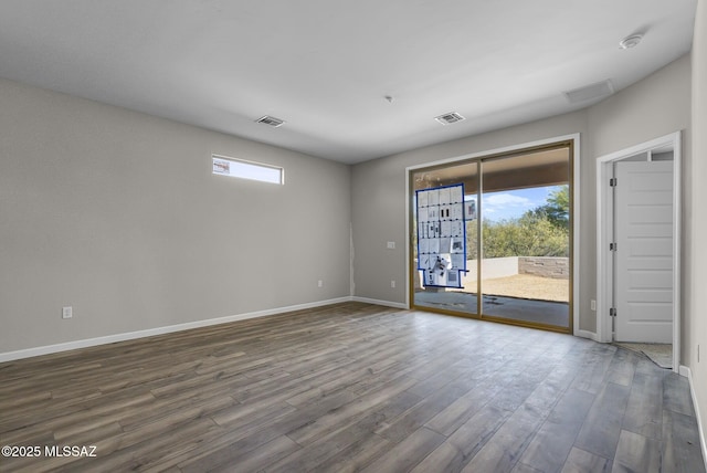spare room with a healthy amount of sunlight, visible vents, and dark wood-style flooring