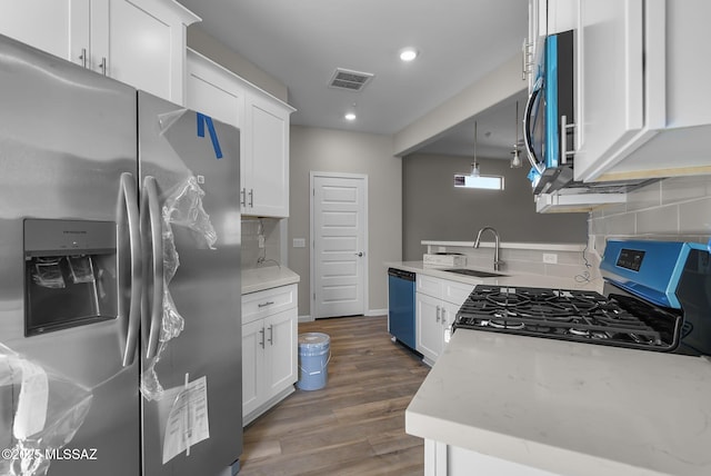 kitchen featuring wood finished floors, visible vents, a sink, appliances with stainless steel finishes, and white cabinetry
