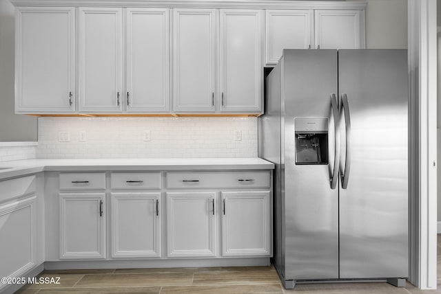 kitchen with white cabinets, backsplash, and stainless steel refrigerator with ice dispenser