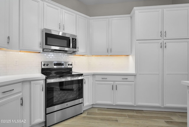 kitchen featuring decorative backsplash, white cabinets, stainless steel appliances, and light wood-type flooring