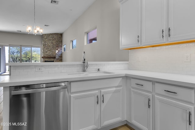 kitchen featuring white cabinetry, stainless steel dishwasher, sink, decorative light fixtures, and kitchen peninsula