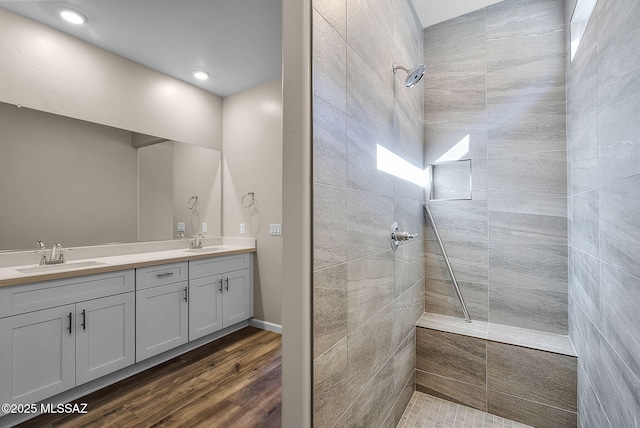 bathroom featuring hardwood / wood-style flooring, tiled shower, and vanity