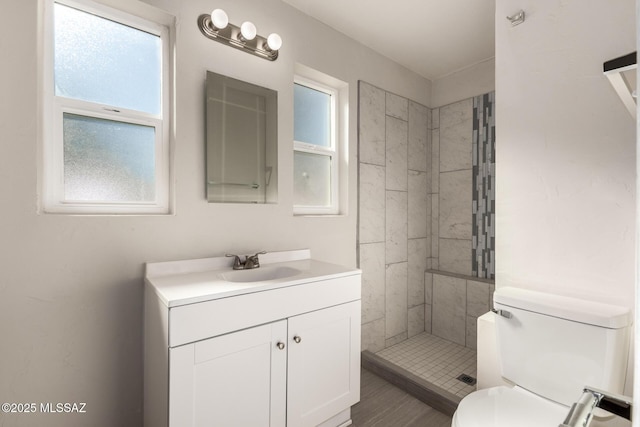 bathroom featuring tiled shower, vanity, and toilet