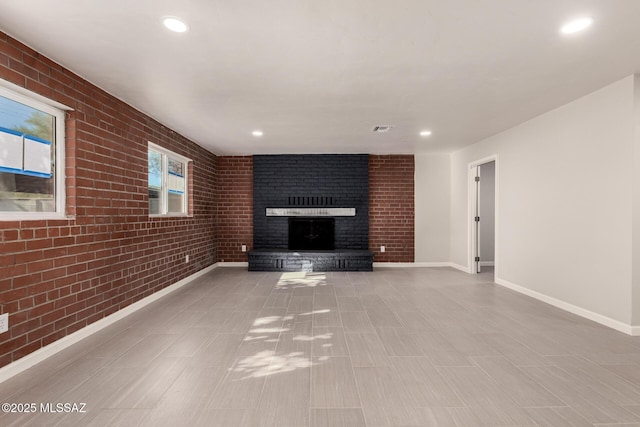 unfurnished living room featuring a brick fireplace and brick wall