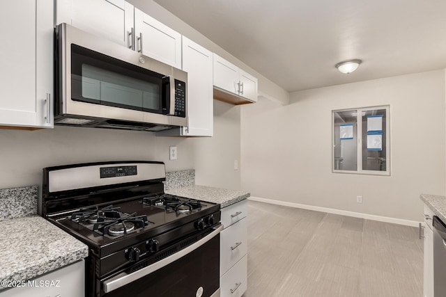 kitchen featuring light stone counters, stainless steel appliances, and white cabinetry