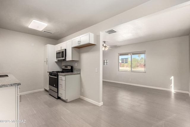 kitchen featuring light stone counters, white cabinets, stainless steel appliances, and ceiling fan