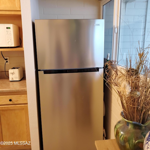 details featuring stainless steel refrigerator and light brown cabinets