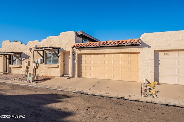 view of front of house featuring driveway, a tiled roof, an attached garage, a pergola, and stucco siding