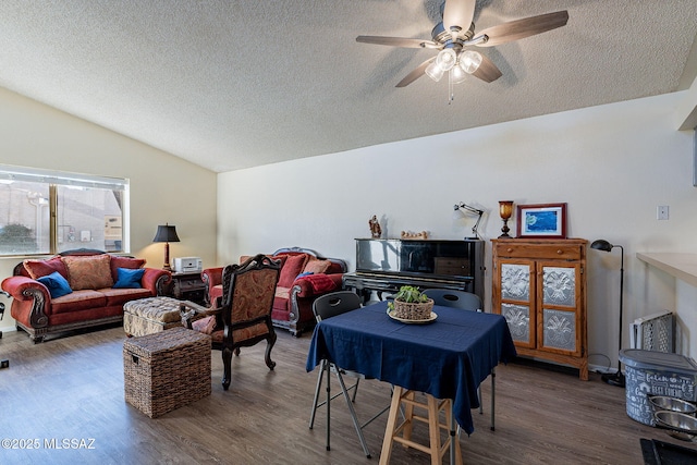 living room with vaulted ceiling, a textured ceiling, wood finished floors, and a ceiling fan